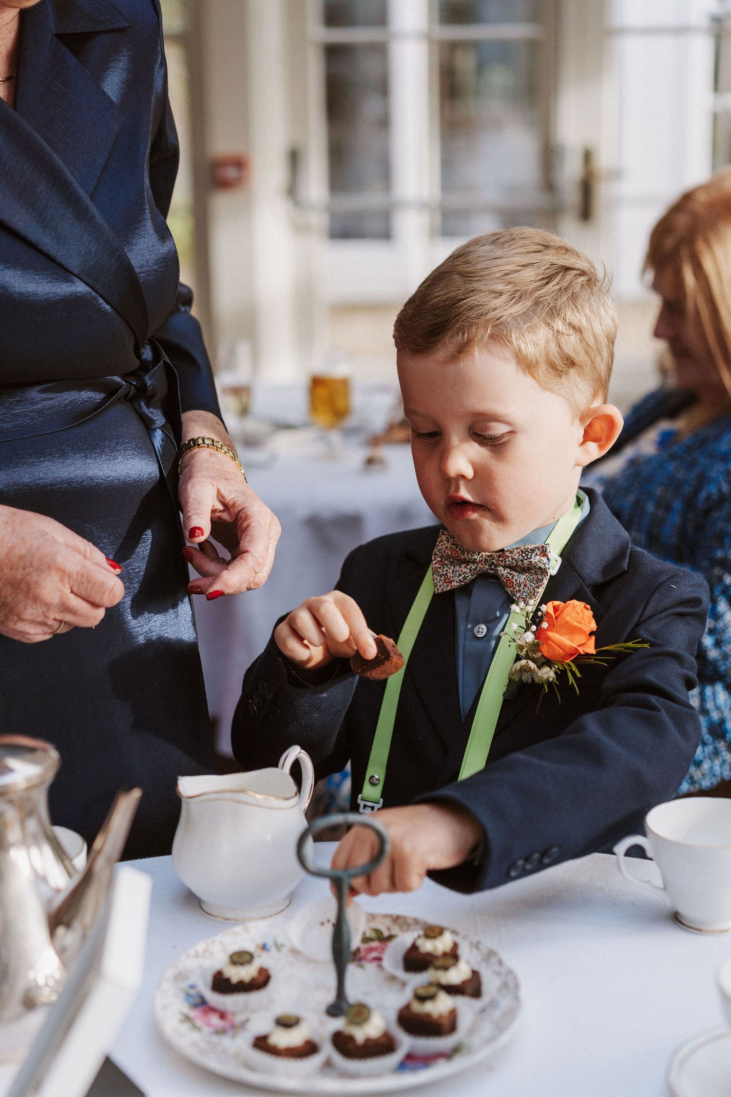 A young child enjoys decorating chocolate cupcakes with green frosting at a white table setting.