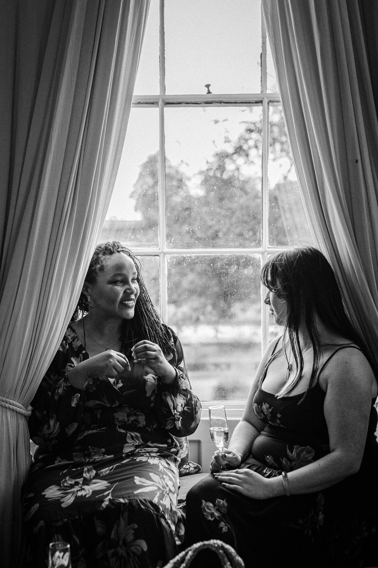 Four black and white photos show a candid conversation between two people seated by a window with curtains.