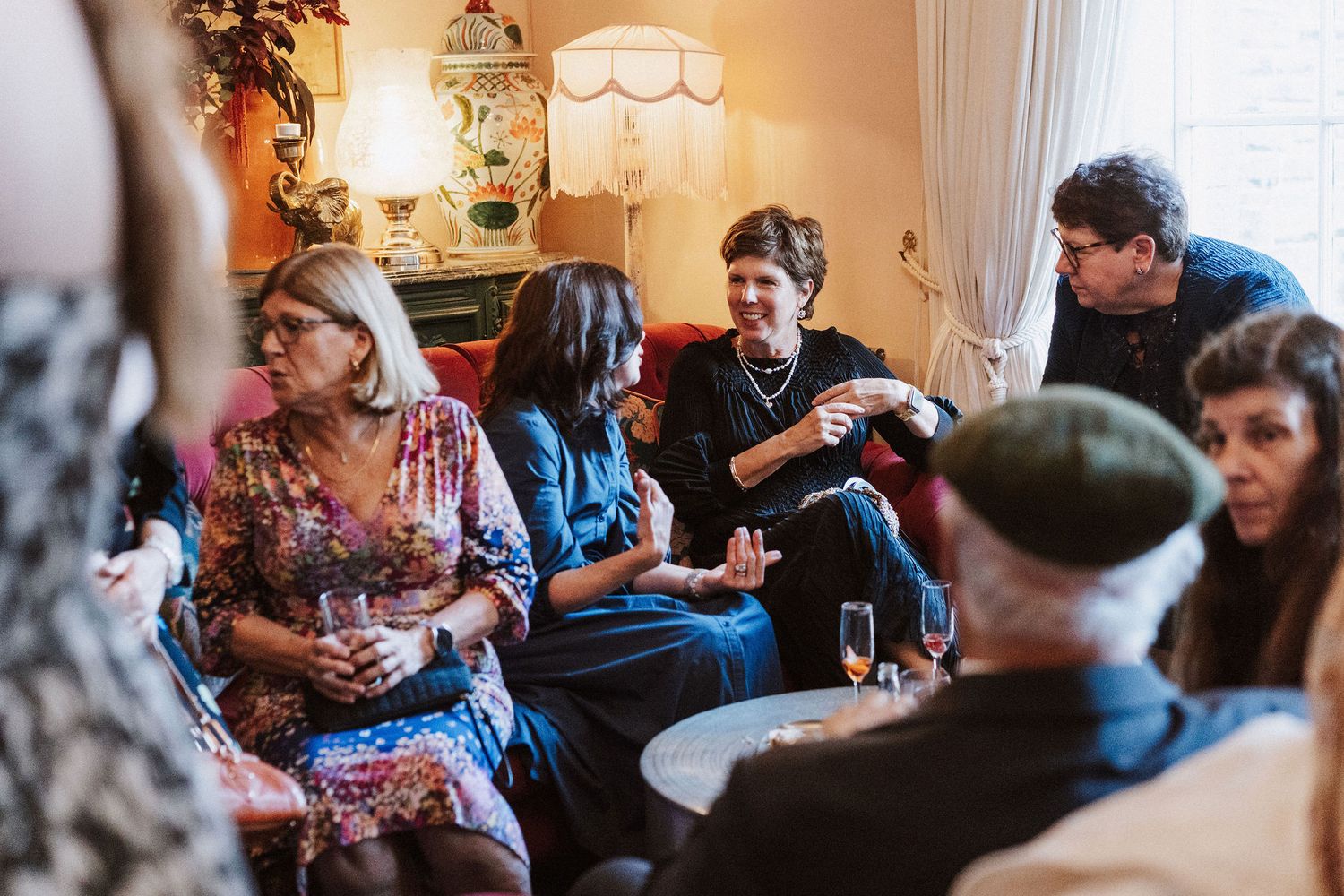 Group of people gathered around a table engaged in casual conversation at a social gathering.
