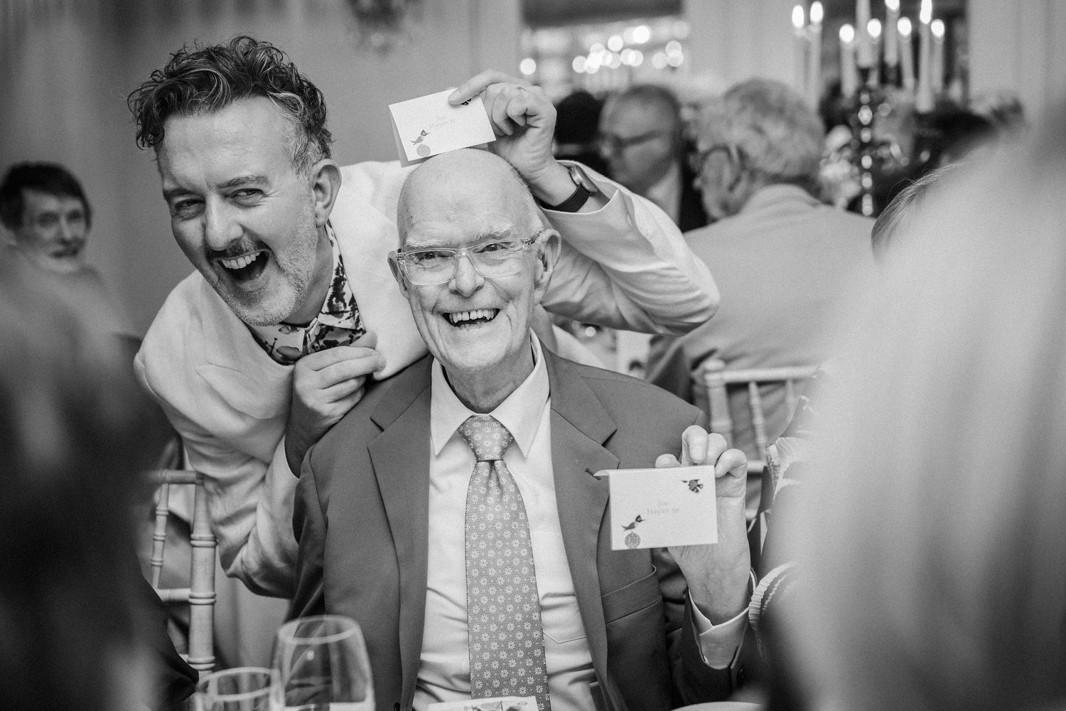Black and white candid photos showing joyful reactions and laughter during a wedding reception celebration.