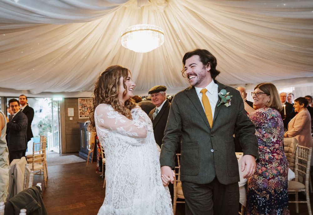 Wedding celebration in a draped reception hall with guests dancing and mingling under elegant lighting.