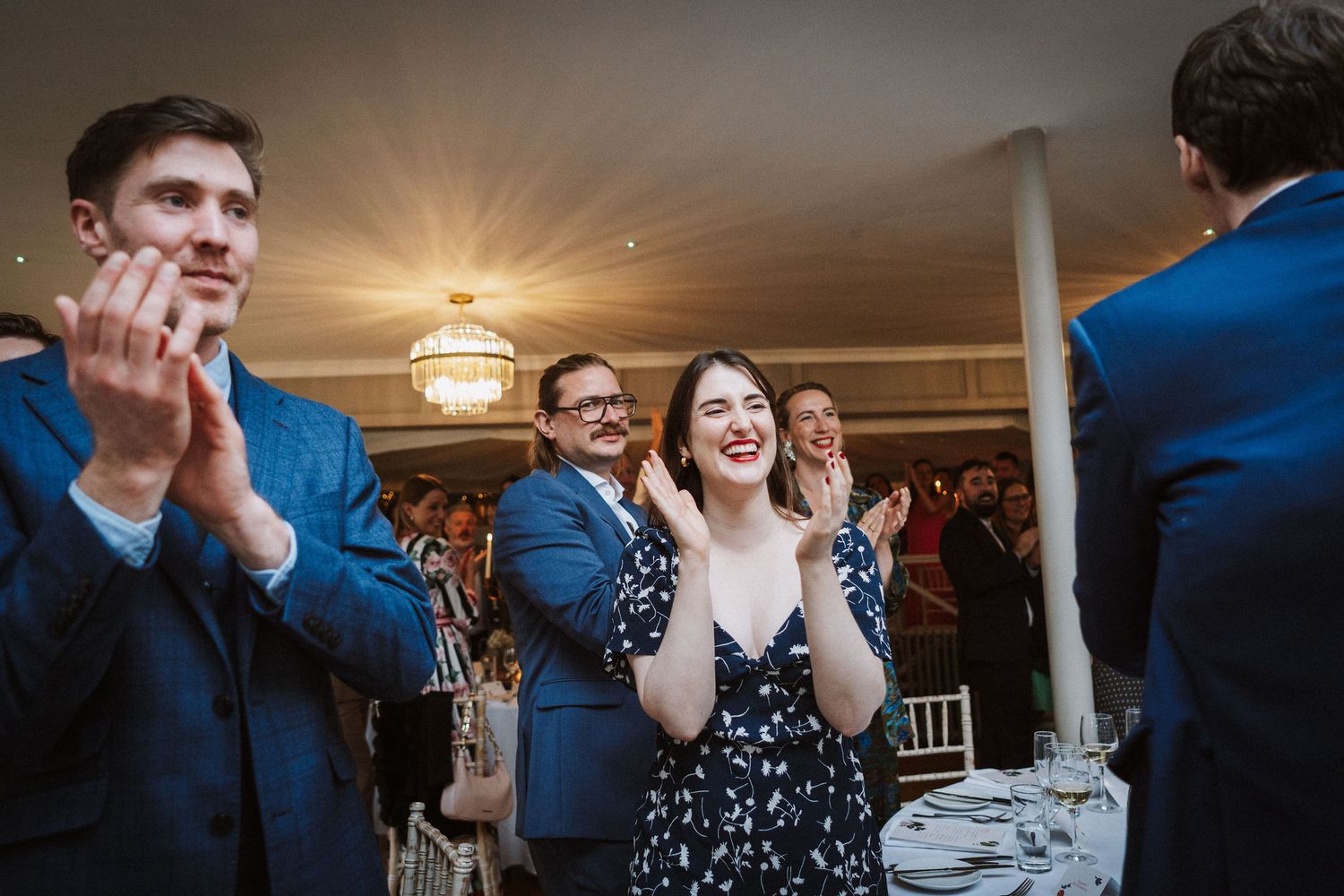 Wedding guests dance and celebrate during a lively reception under warm lighting and elegant decor.