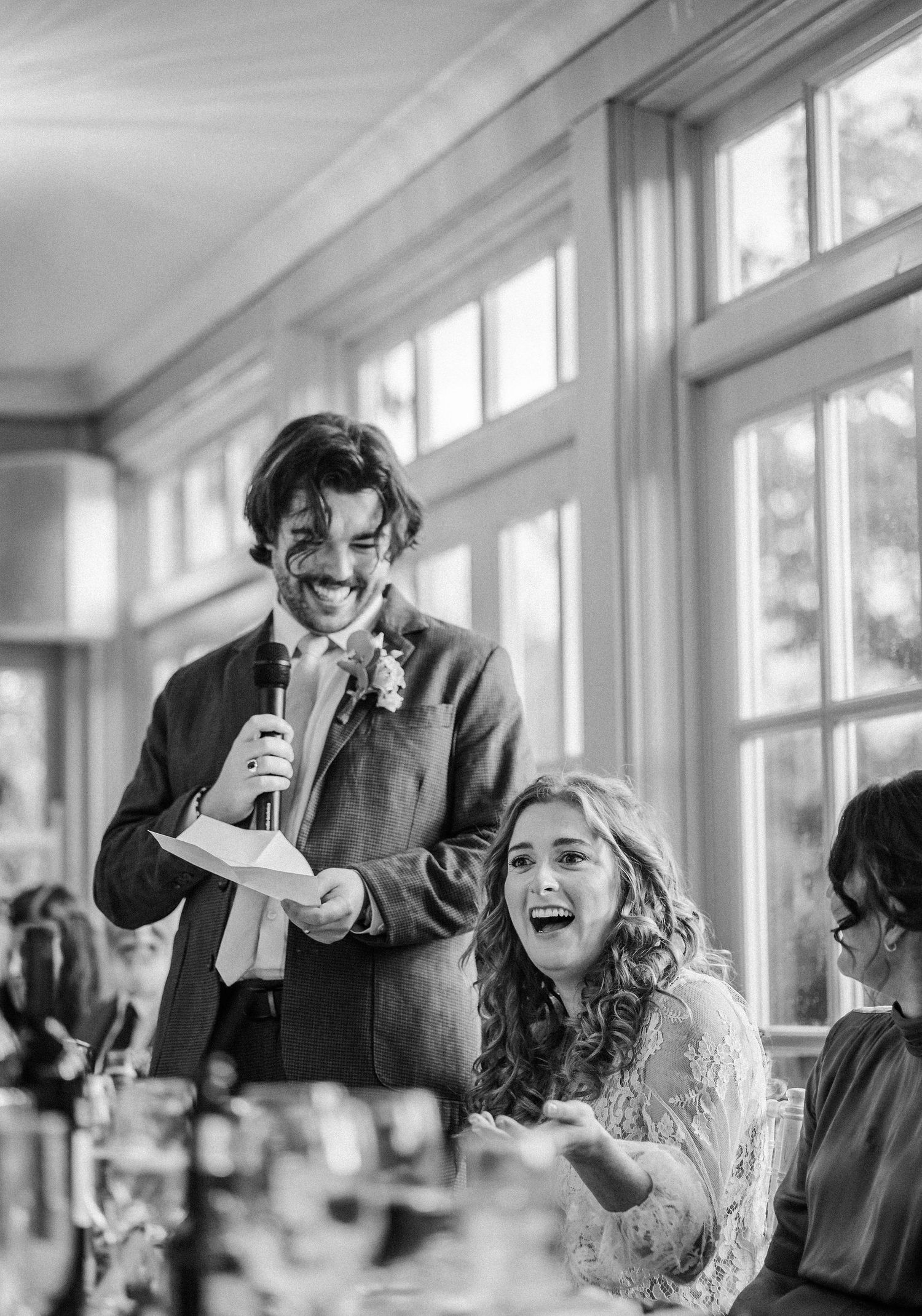 A series of black and white candid photos showing a joyful wedding reception scene with laughter and celebration.