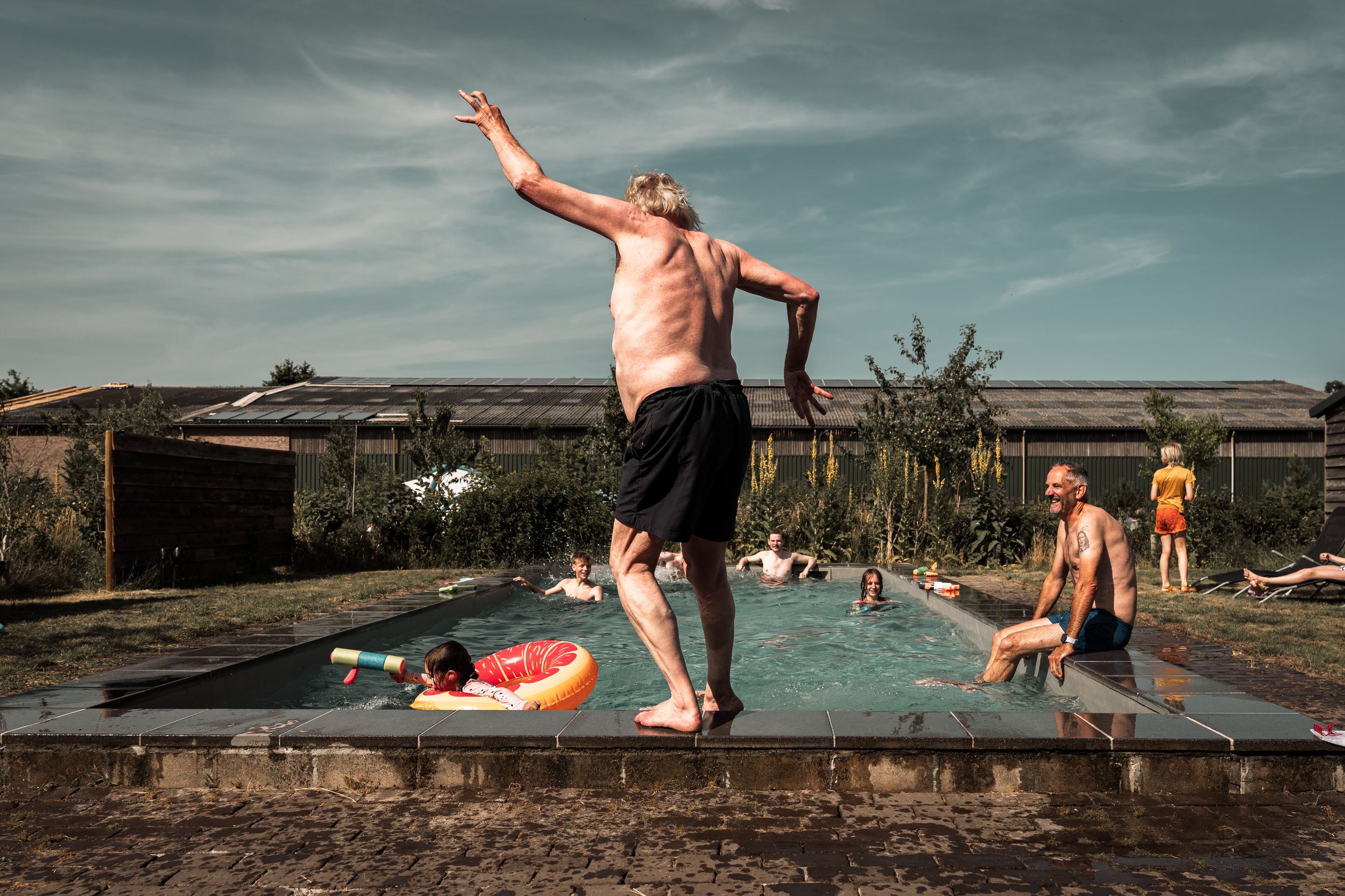 People enjoying a summer day at a swimming dock with multiple action shots of jumping and splashing in the water.