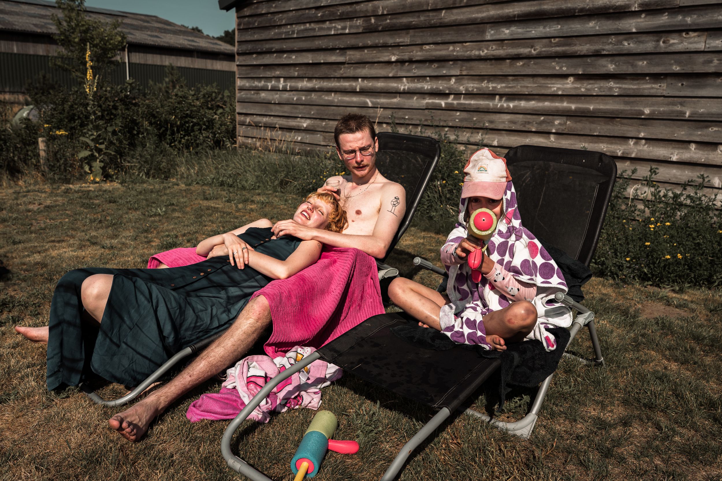 People lounging and relaxing on outdoor furniture in a backyard setting during a sunny summer day.