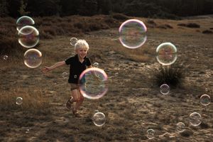 A sequence of photos showing giant soap bubbles floating across a desert-like landscape at sunset.