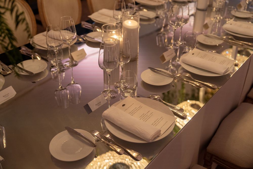 An elegant table setting at a fine dining restaurant with white linens, wine glasses, and ambient lighting.