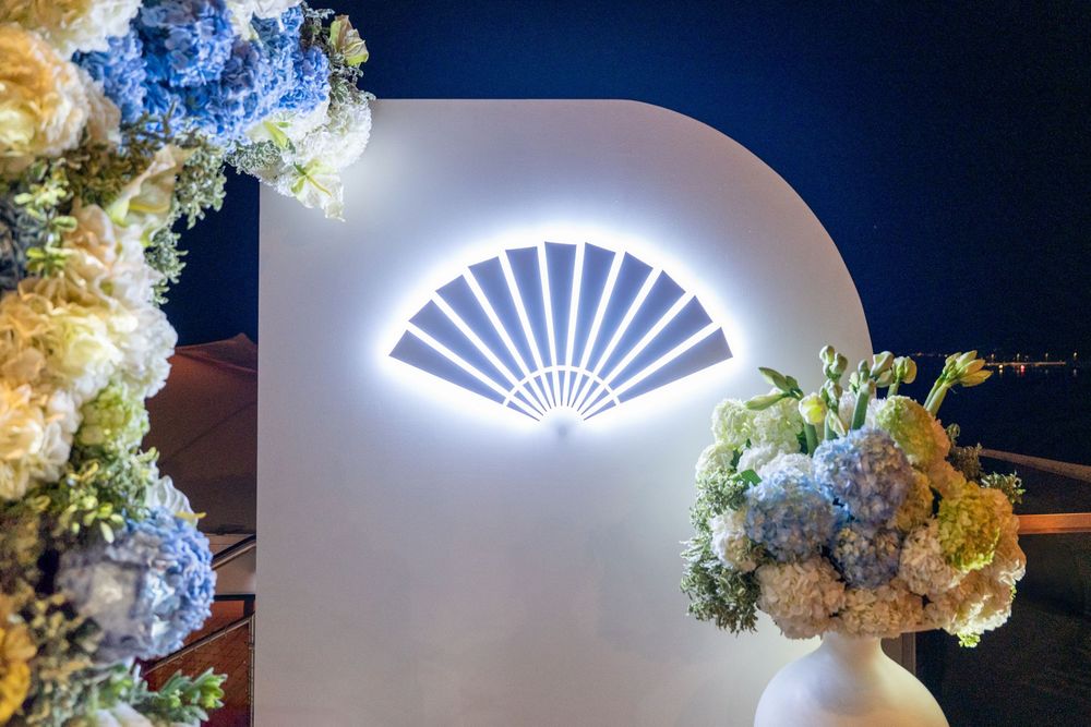 White floral arrangements and illuminated fan-shaped lighting create an elegant wedding reception decor display.