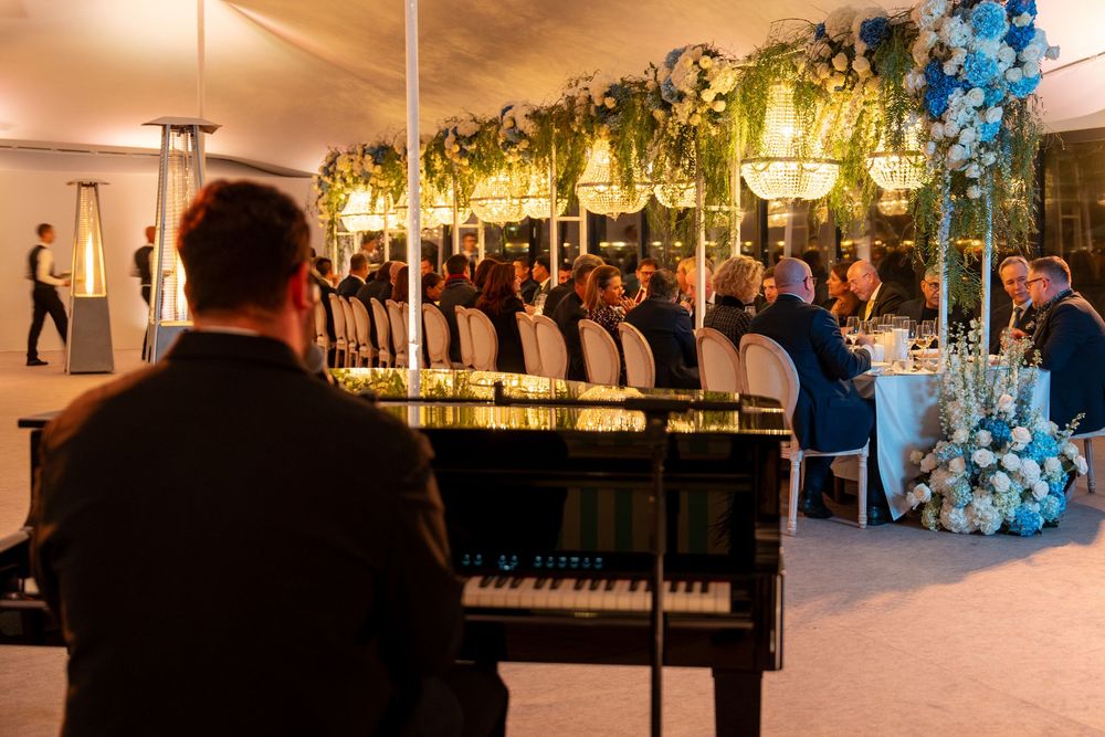 Panoramic view of an elegant wedding venue with warm lighting, floral decorations and guests mingling in formal attire.