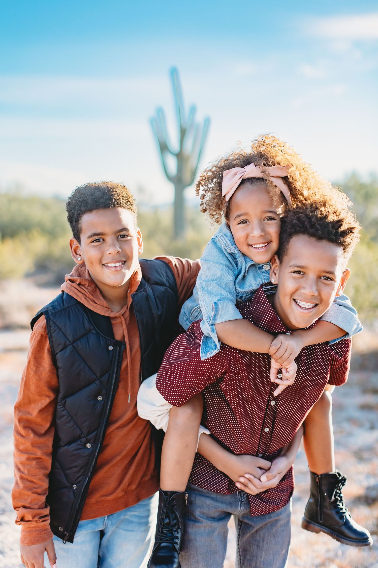 Playful piggyback ride scene in a desert landscape with saguaro cactus in the background.