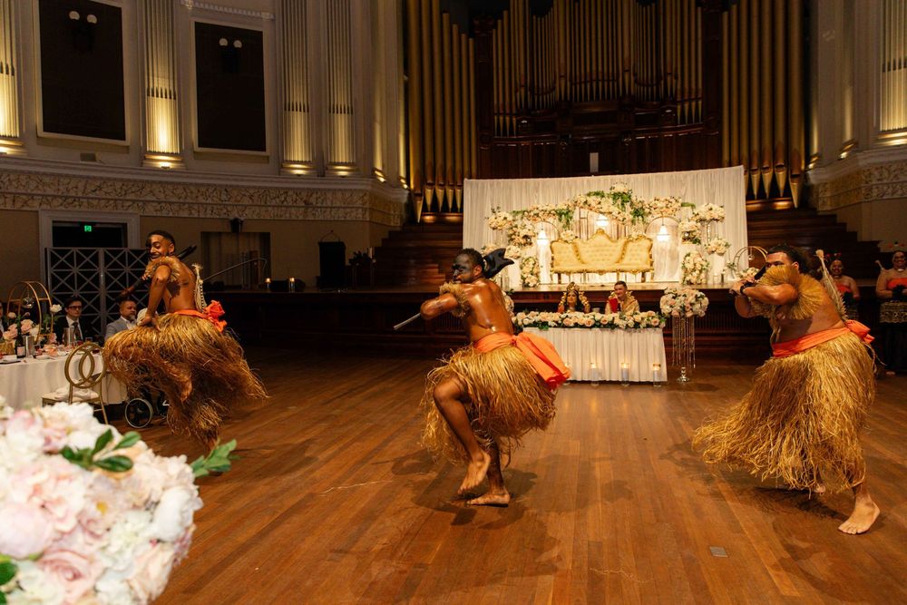 Traditional African dancers in grass skirts perform energetically at Indian wedding reception hall.