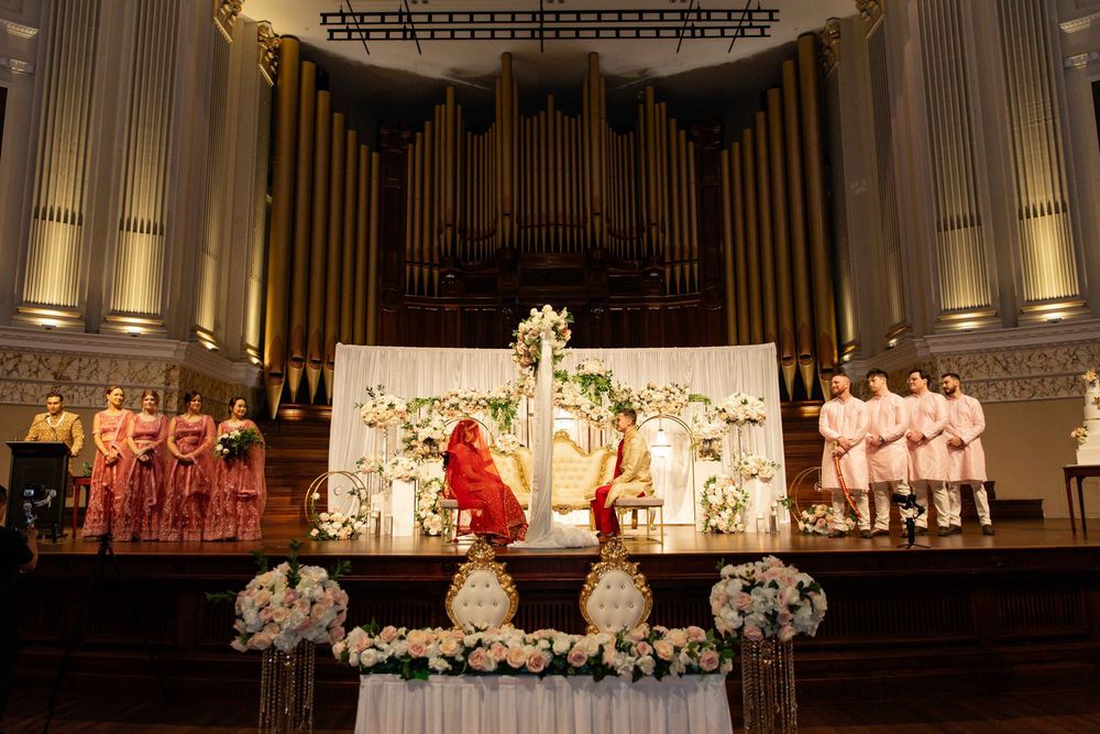 Indian wedding ceremony at ornate church venue with bride and groom at decorated floral altar.