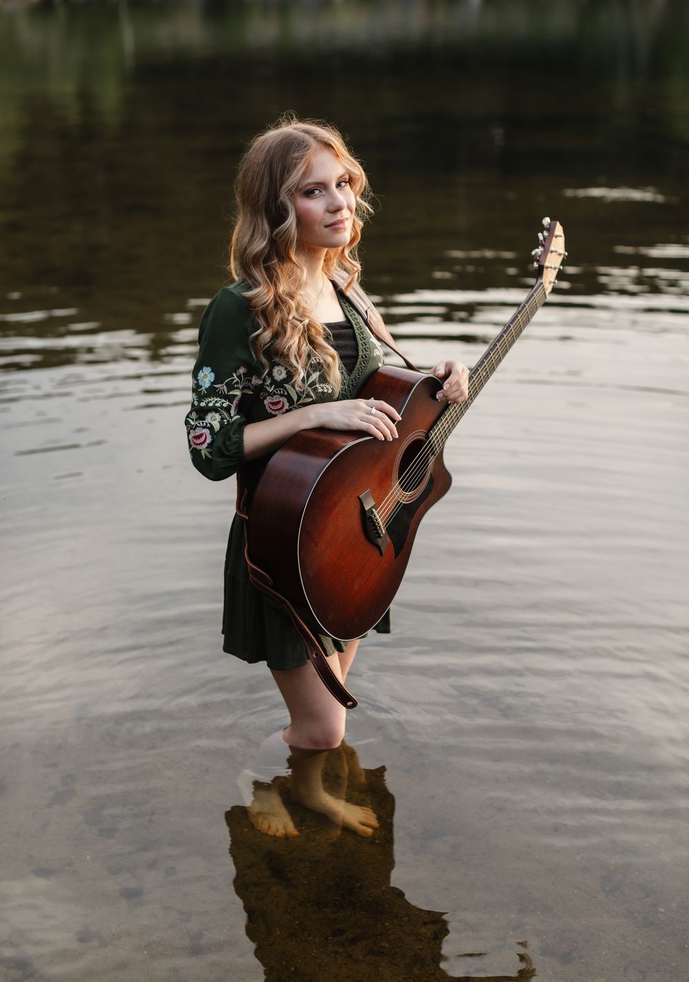 Rachel Delong, Christian musician, wears a green dress and stands in Lake Sunapee holding her guitar for portraits. Senior photographer NH.