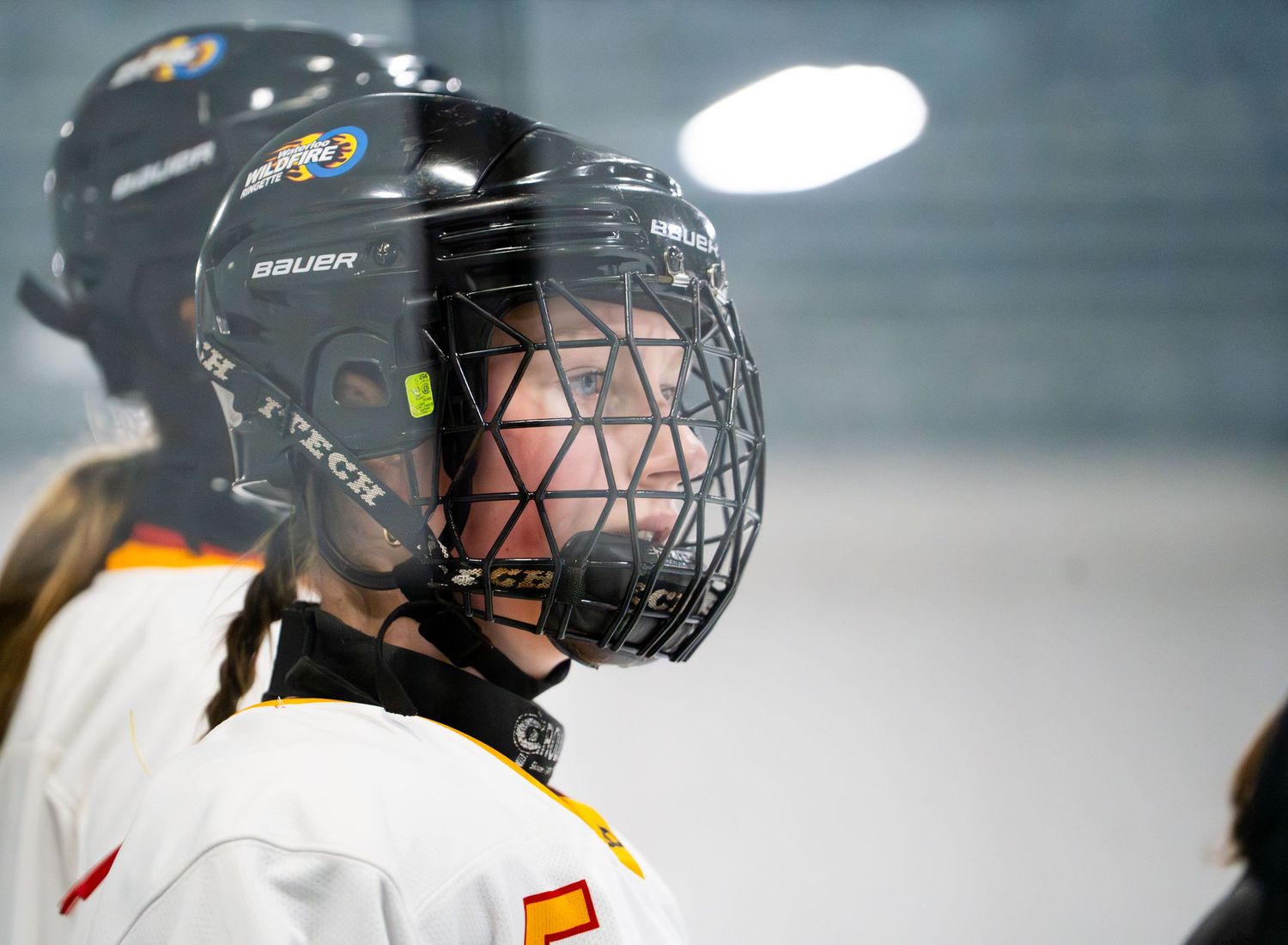Ringette player in protective gear and cage helmet during game.