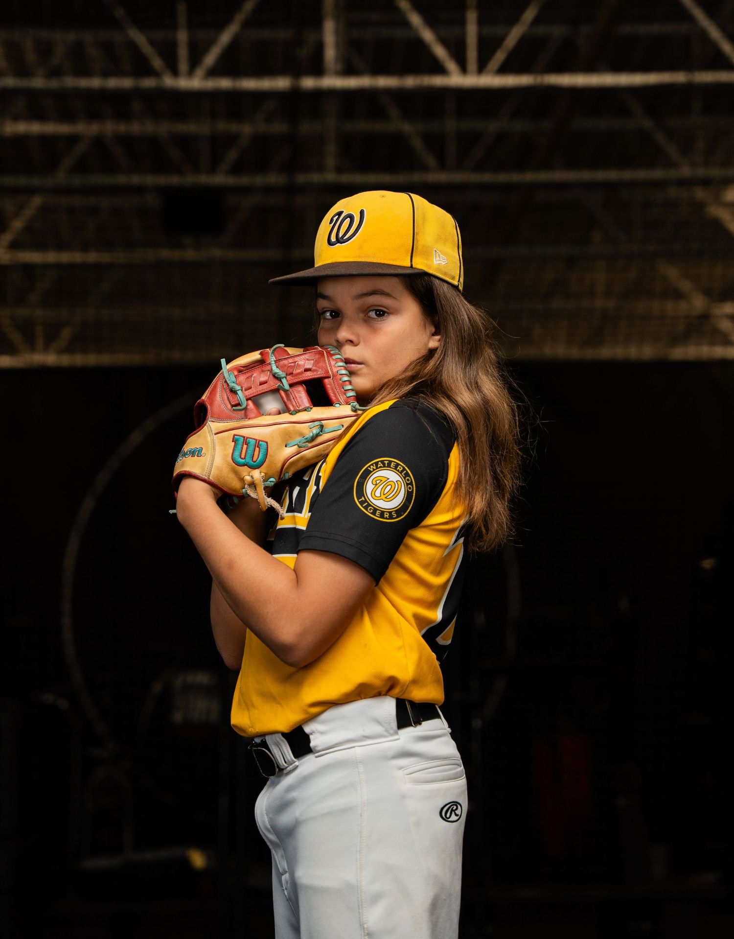 Baseball player in yellow and black uniform practicing pitching stance.