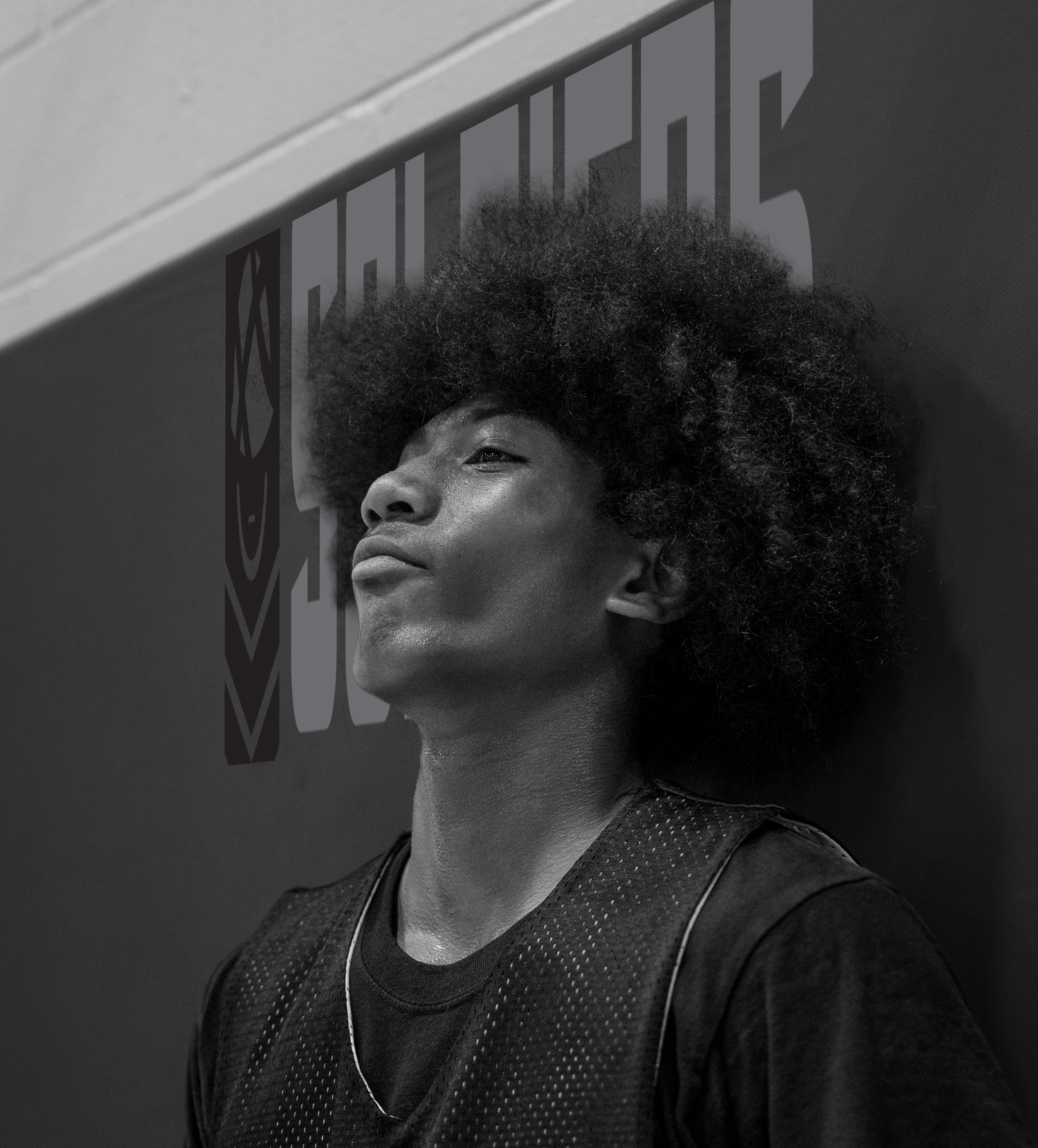 Basketball player in dark mesh jersey shown in dramatic black and white profile.