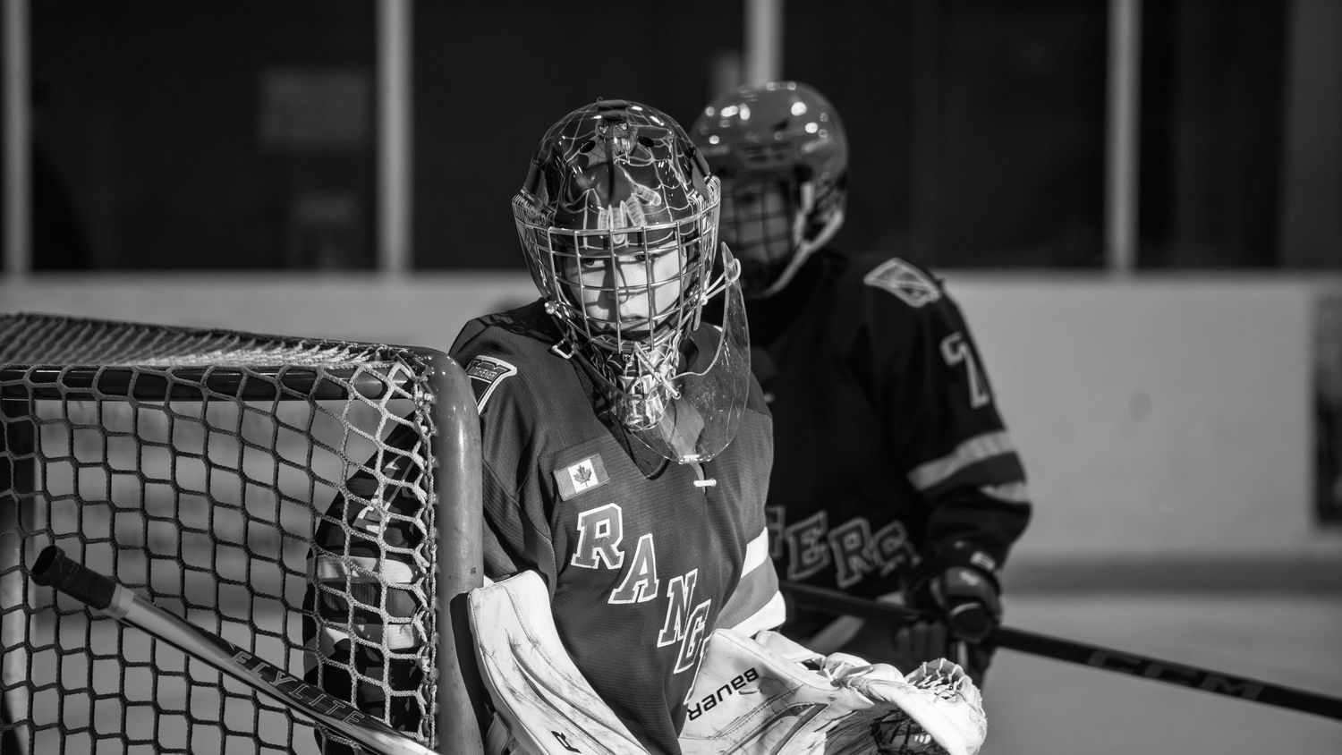 Hockey players facing off near the goal net during an intense game moment.