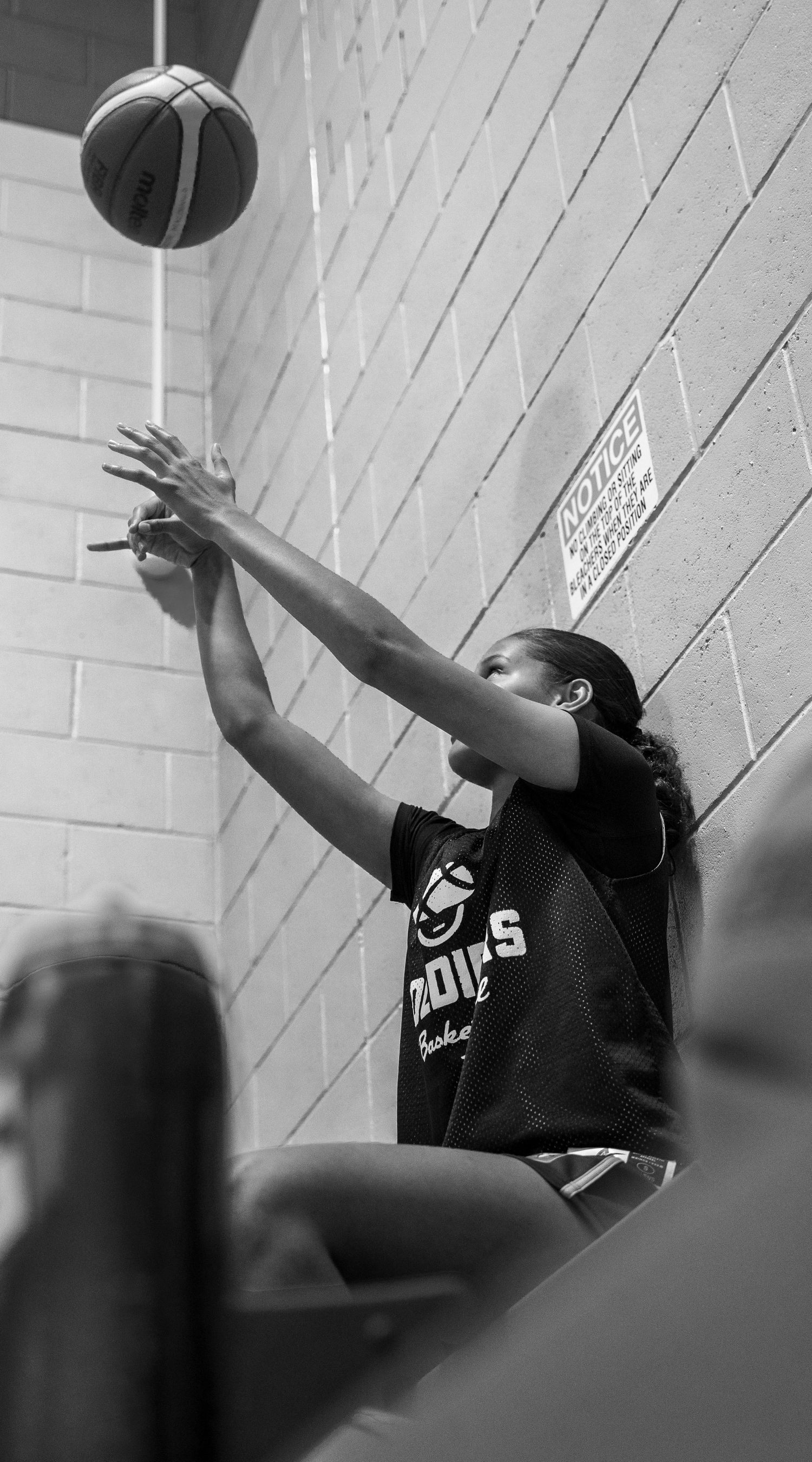 Basketball player practicing shooting drills against a white brick wall.