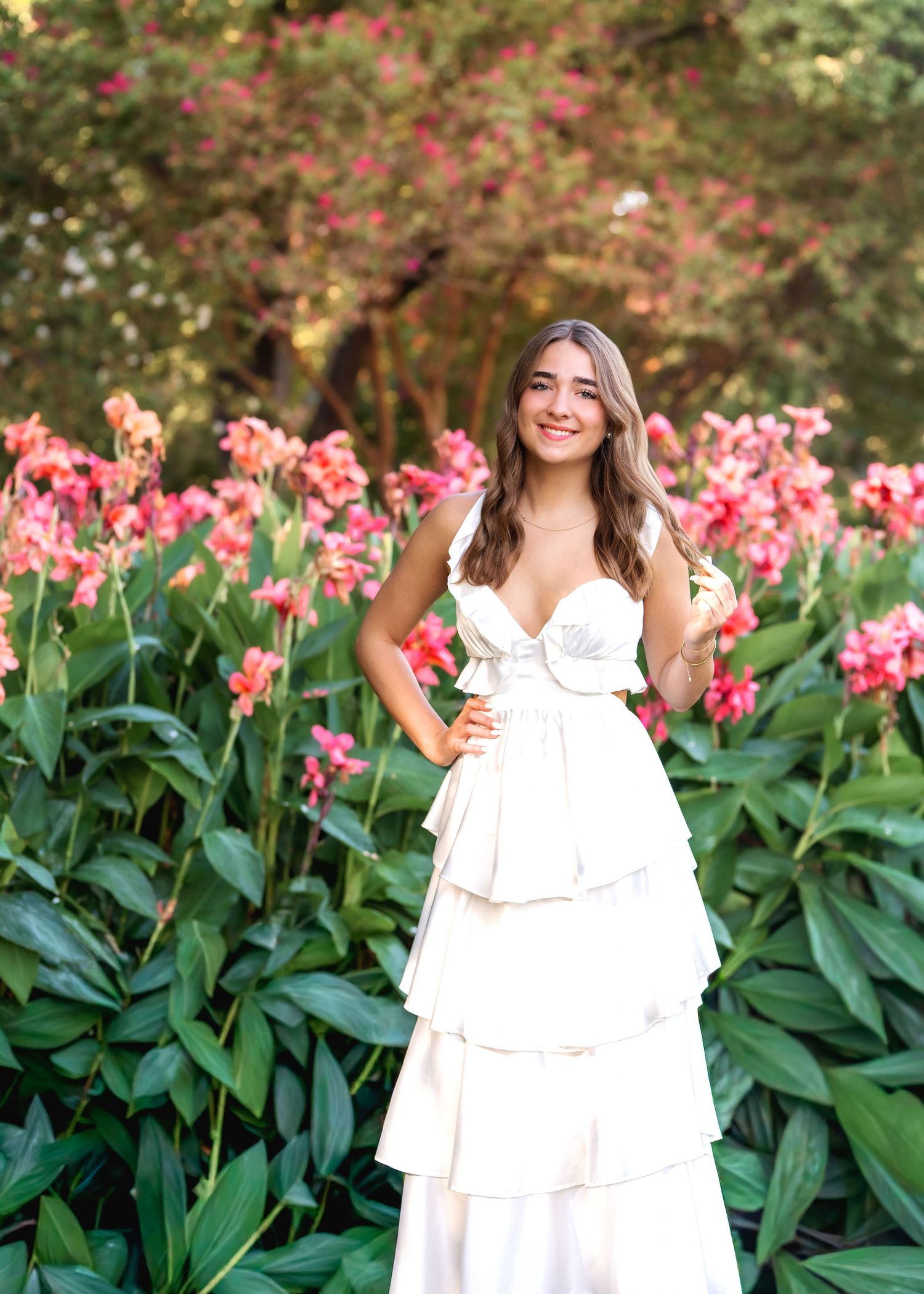 Someone in a yellow dress poses among vibrant pink cherry blossoms on a bright spring day.