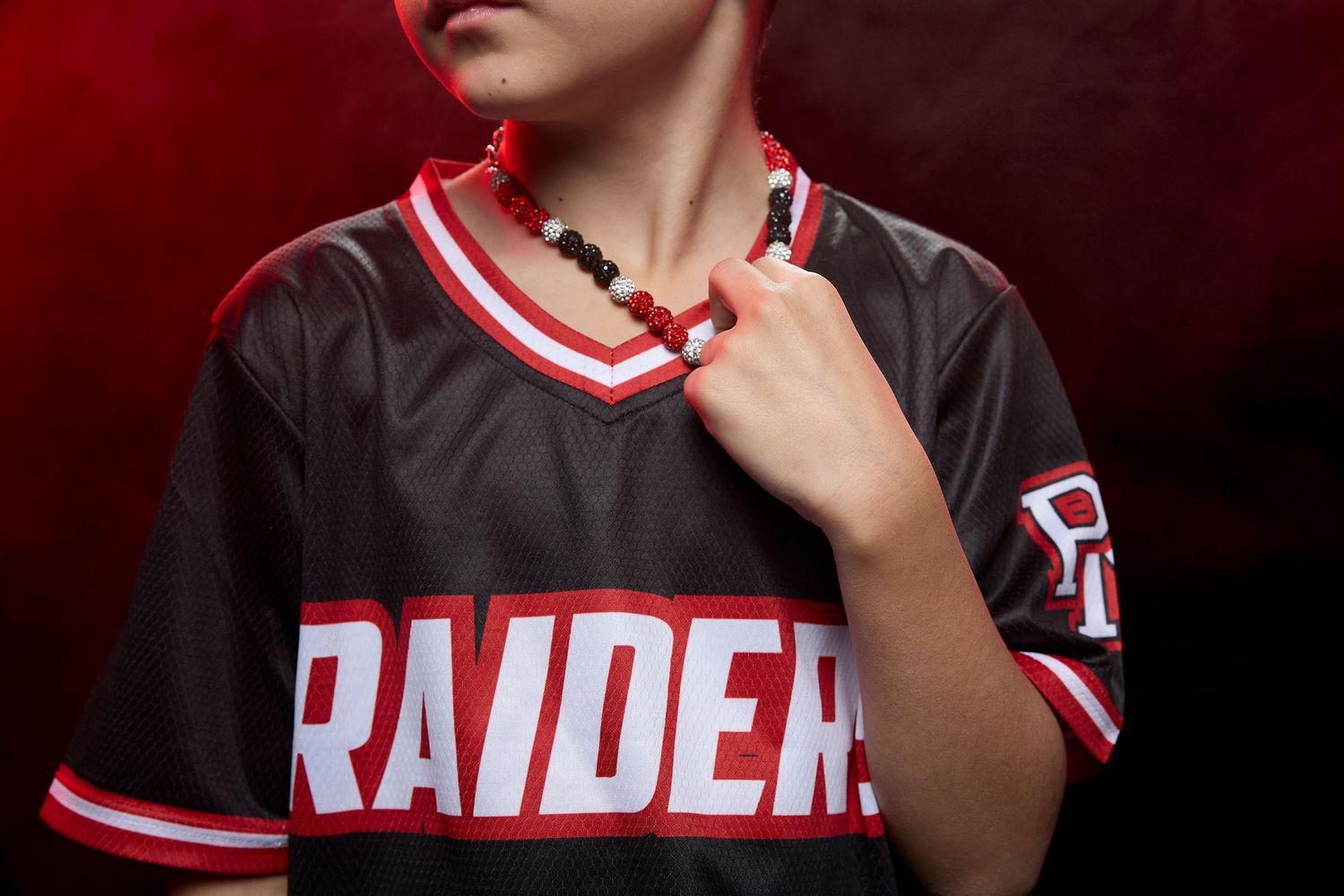 A row of sports team photos showing players in black and red uniforms with Raider team branding.