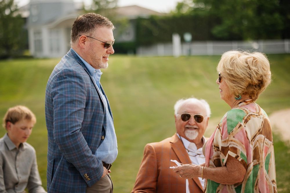 Wedding guests enjoying champagne and conversation during an outdoor garden reception celebration.