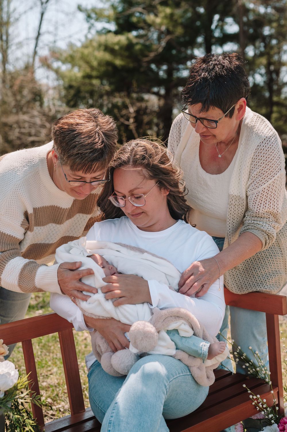 A sequence of tender moments showing parents cradling their newborn baby on a wooden bench outdoors.