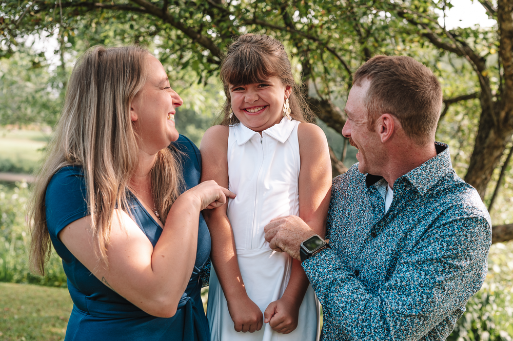 Family in coordinating blue and white outfits sharing joyful moments together outdoors in a natural setting.