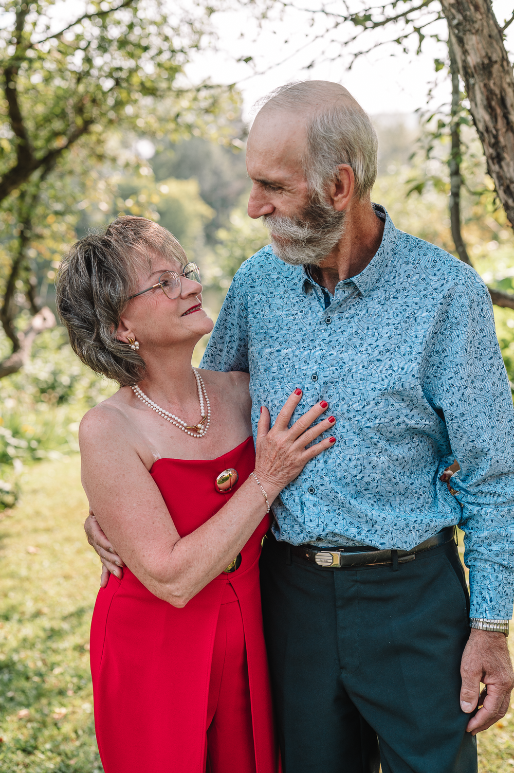 A couple in red and blue outfits share tender moments outdoors in a series of candid shots.