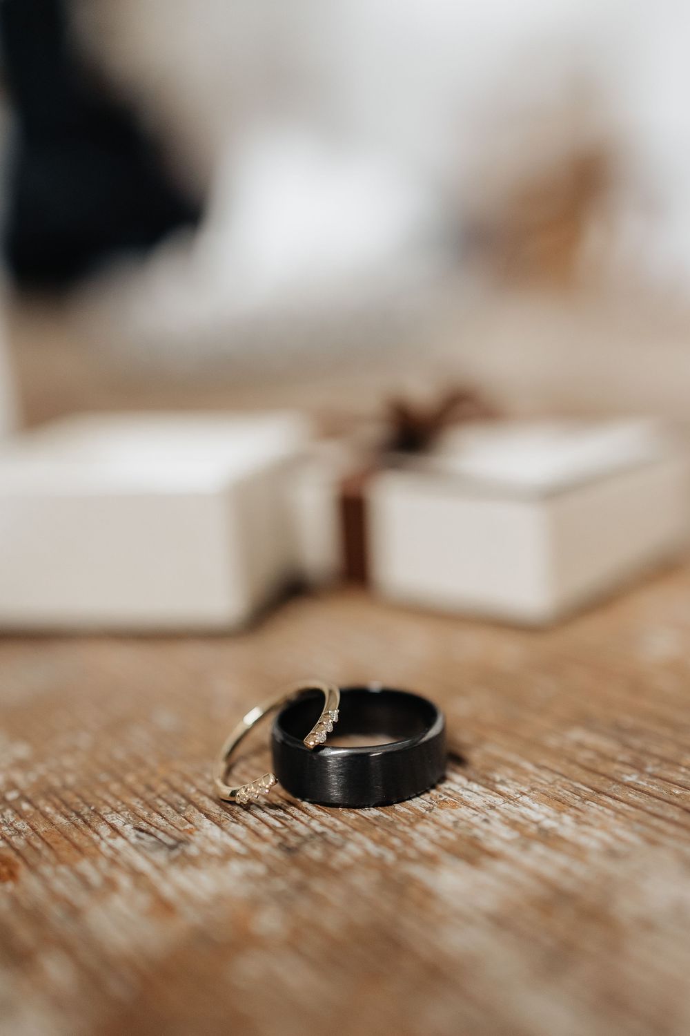 Two wedding rings sit on a rustic wooden surface in soft focus, symbolizing marriage and commitment.