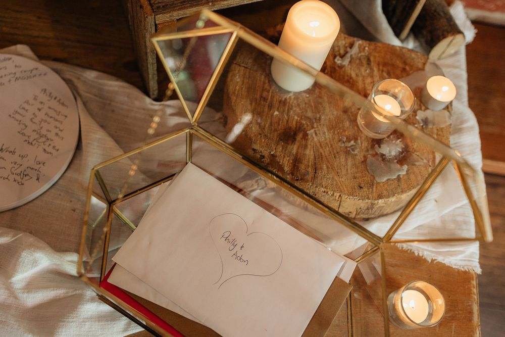 Wedding reception table details with handwritten cards and glowing candles creating intimate ambiance.