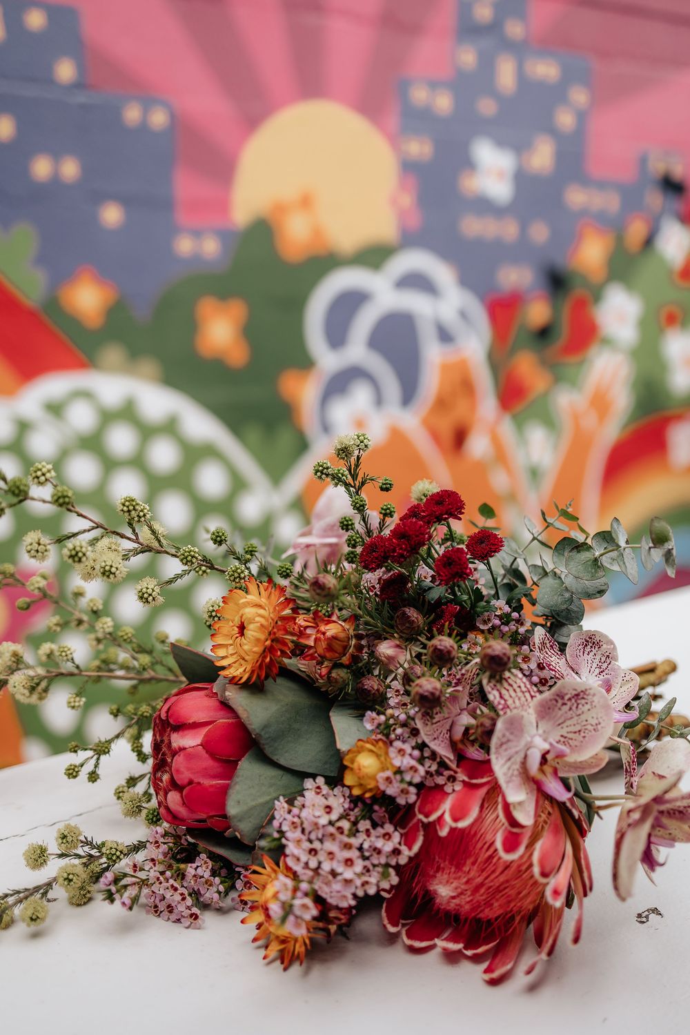 A beautiful floral crown made with pink, red and white flowers and green foliage arranged in a delicate curved design.