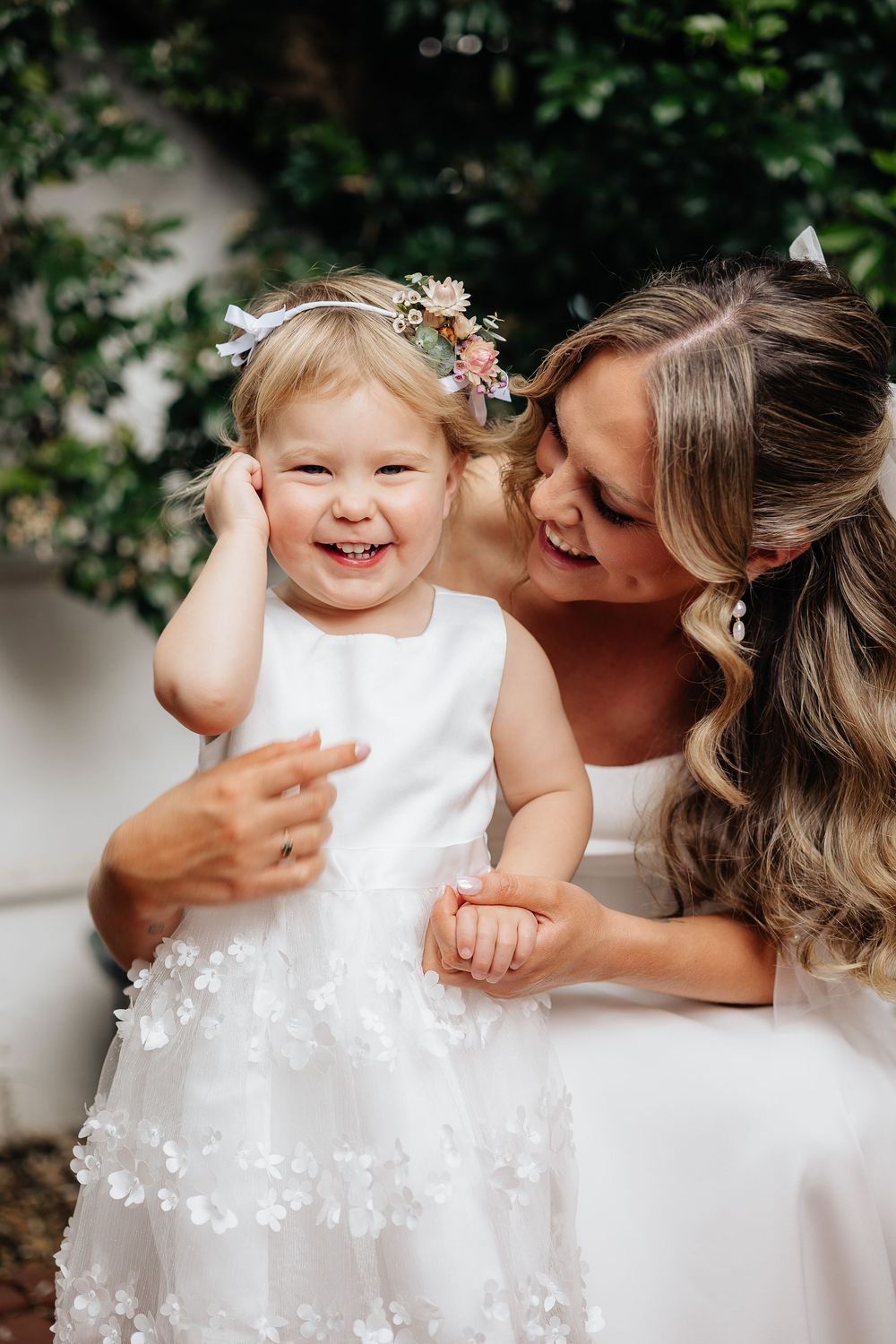 Sweet candid moments between a flower girl in a white dress and her loved one.