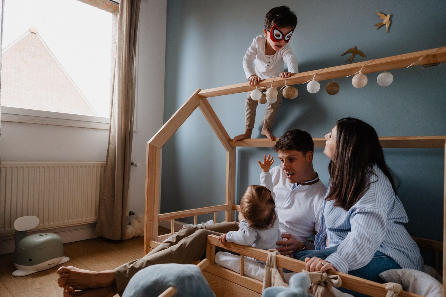 Petit garçon deguise en spiderman grimpe sur son lit cabane pendant une séance grossesse en famille Lille dynamique.