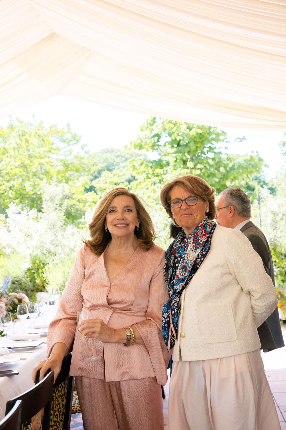 A group in coordinated pink and white outfits share a candid moment at an outdoor celebration.