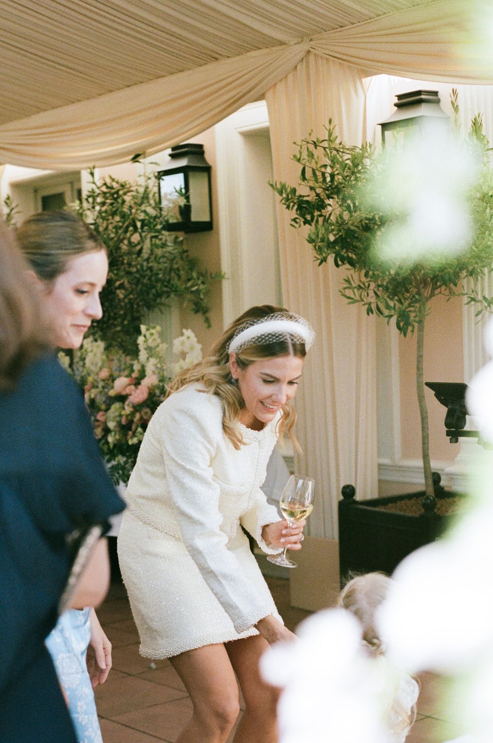 A series of candid moments captured in a white-draped reception space decorated with greenery and soft lighting.