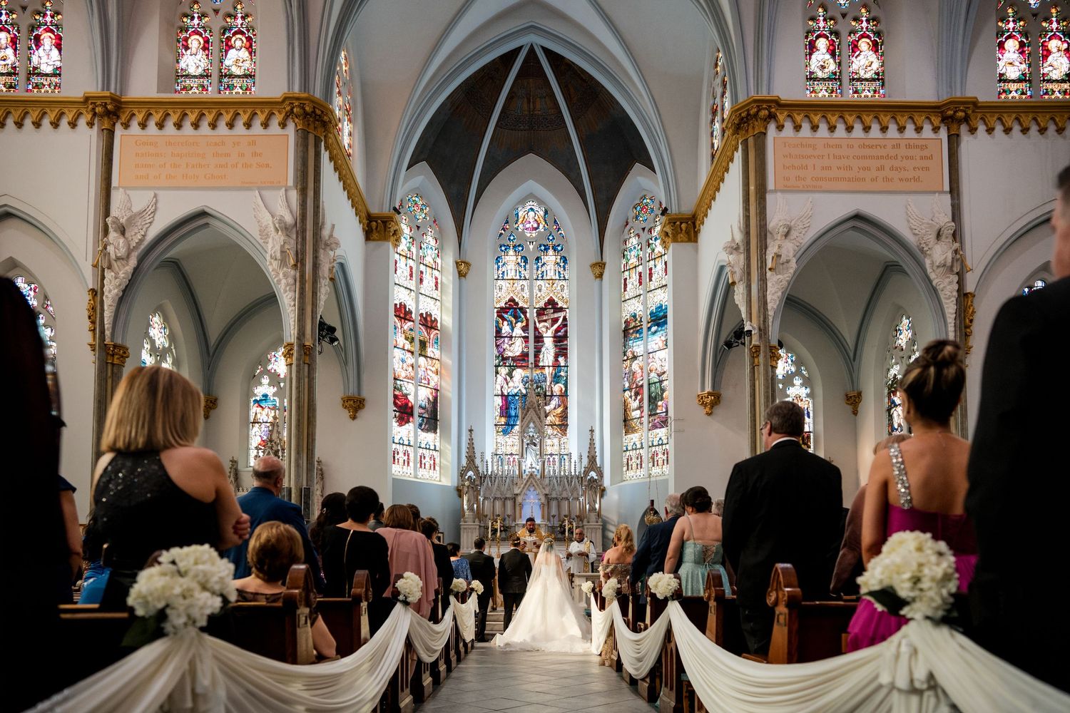A panoramic view of an ornate church interior with pews, columns, and an elaborate altar during a service.