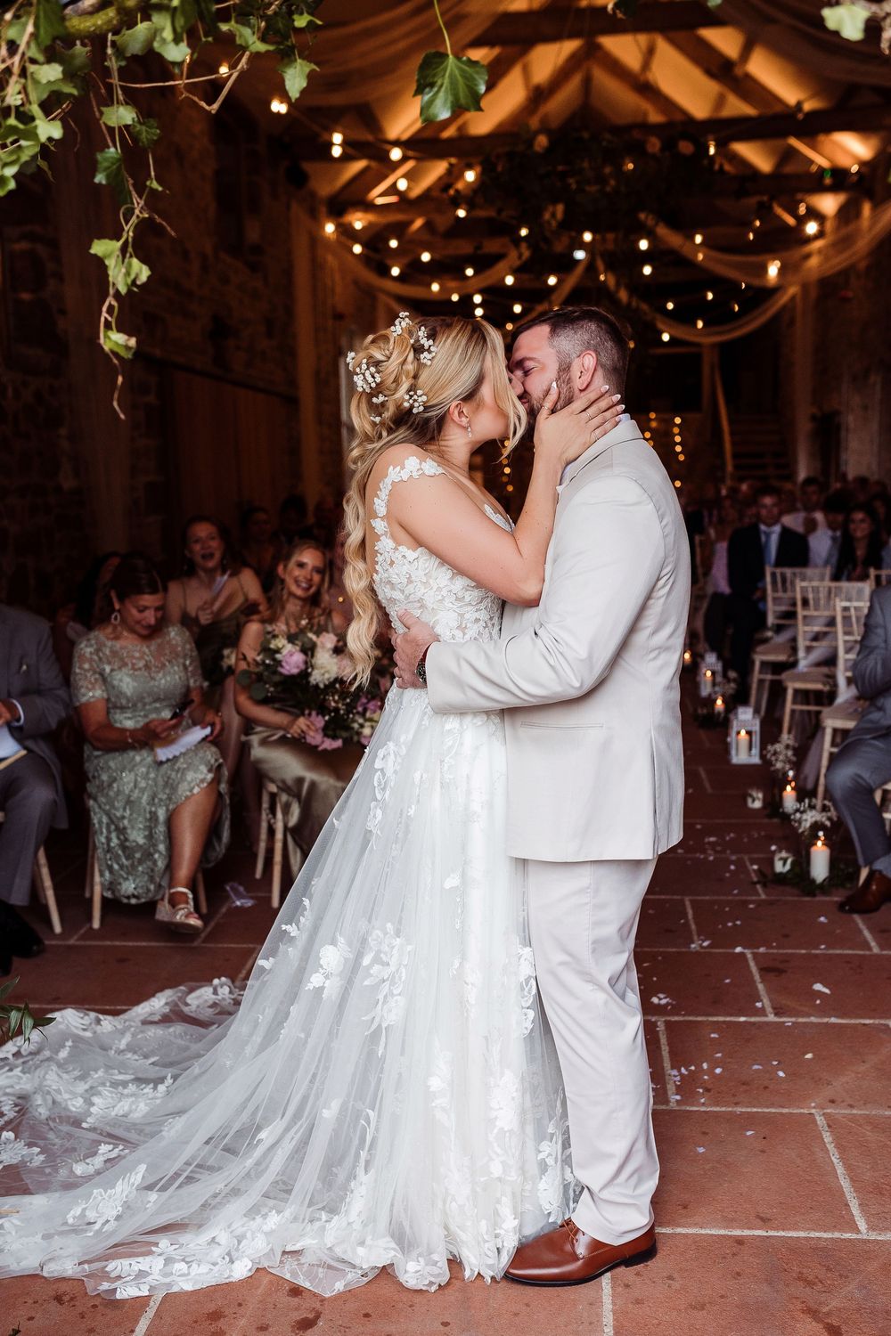 Couple shares their first dance as newlyweds in a rustic barn venue decorated with twinkling lights.