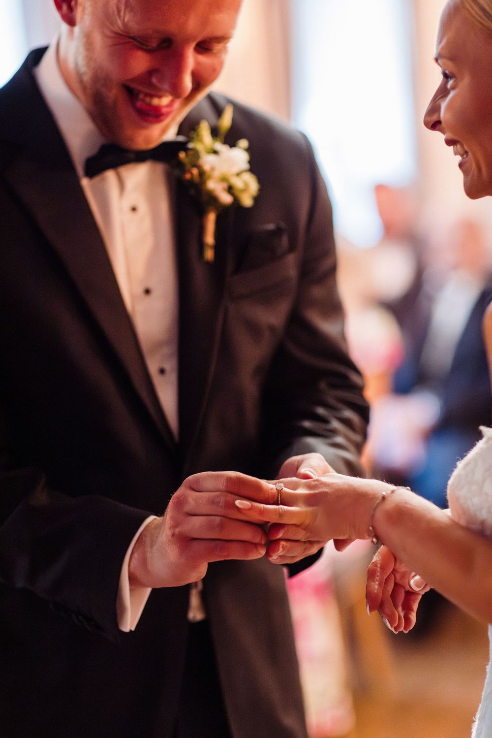 Close-up sequence of wedding ring exchange between couple's hands during traditional ceremony.
