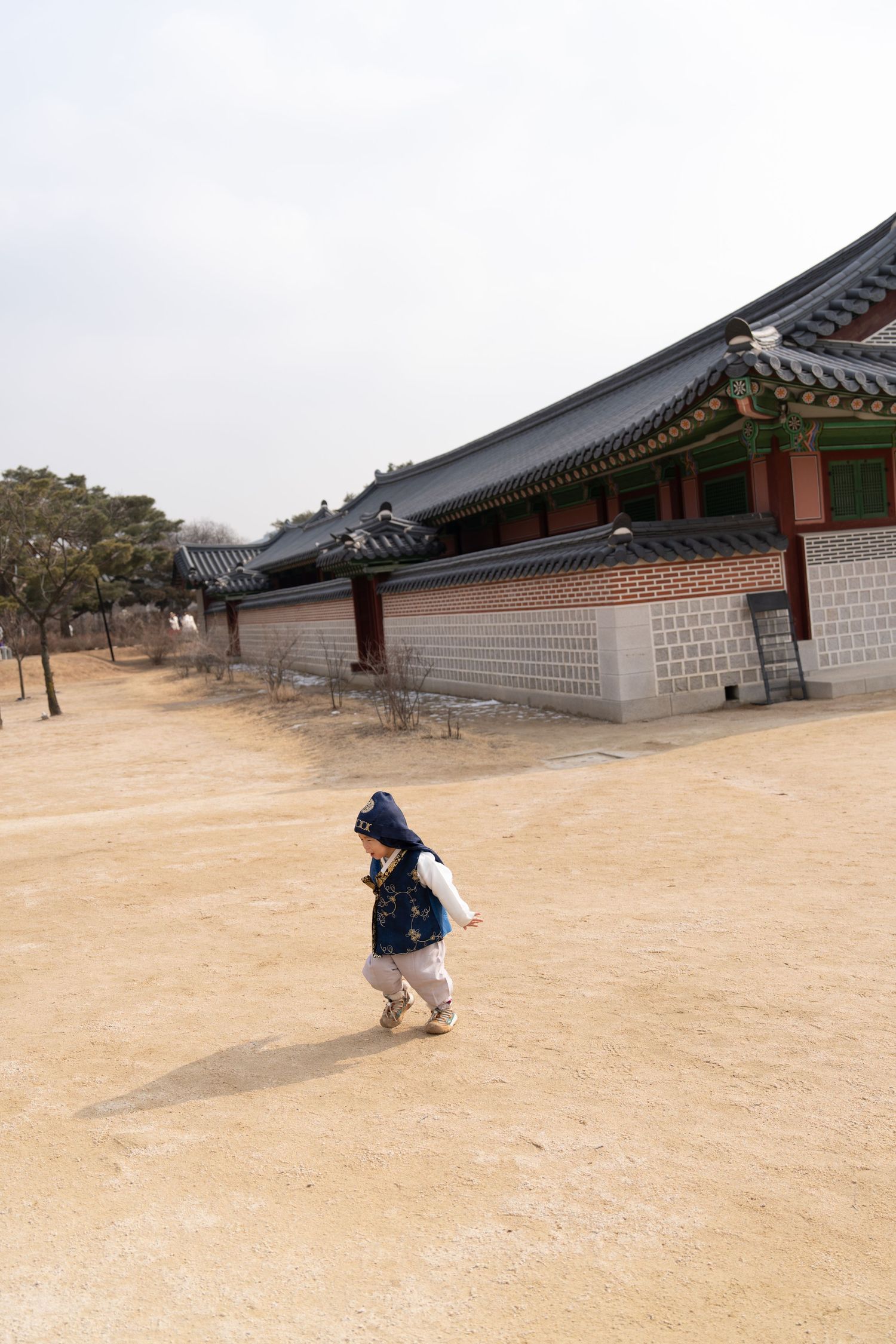 A person takes photos at a traditional Korean palace courtyard with stone walls and traditional architecture.