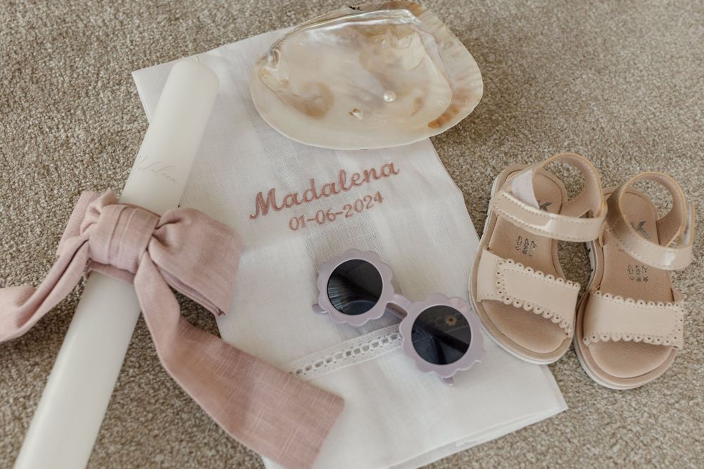 Personalized baby accessories including sunglasses, sandals and a monogrammed white garment.