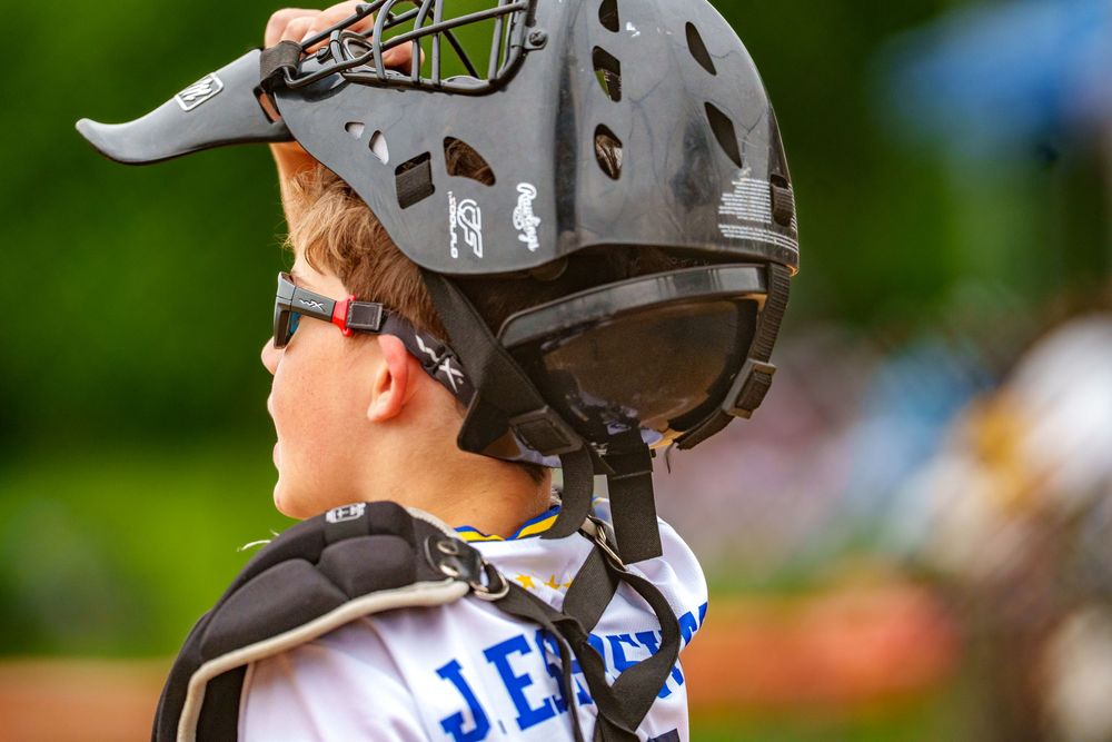 Youth baseball catcher watching the field in full gear, close-up, SportsFox Photography.