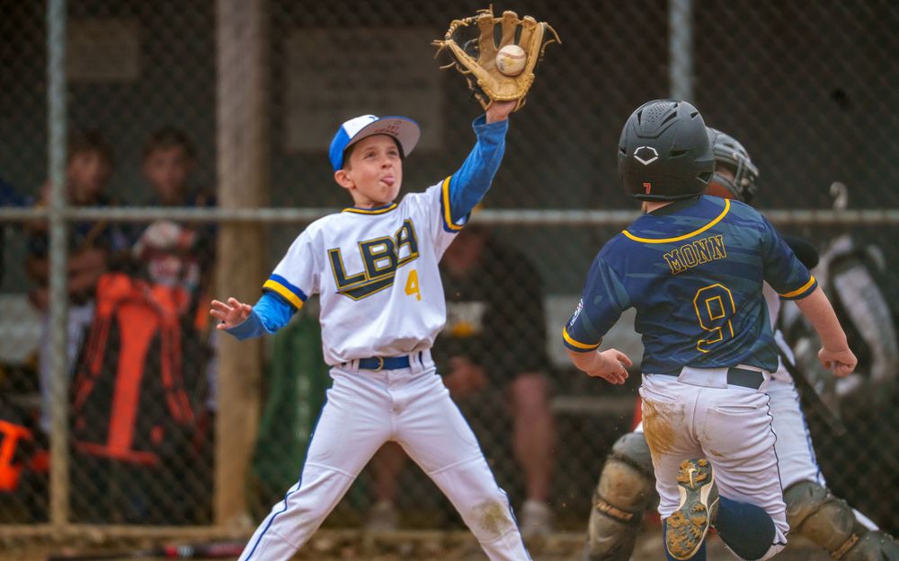 Youth infielder making a play, glove outstretched during a baseball game, SportsFox Photography.