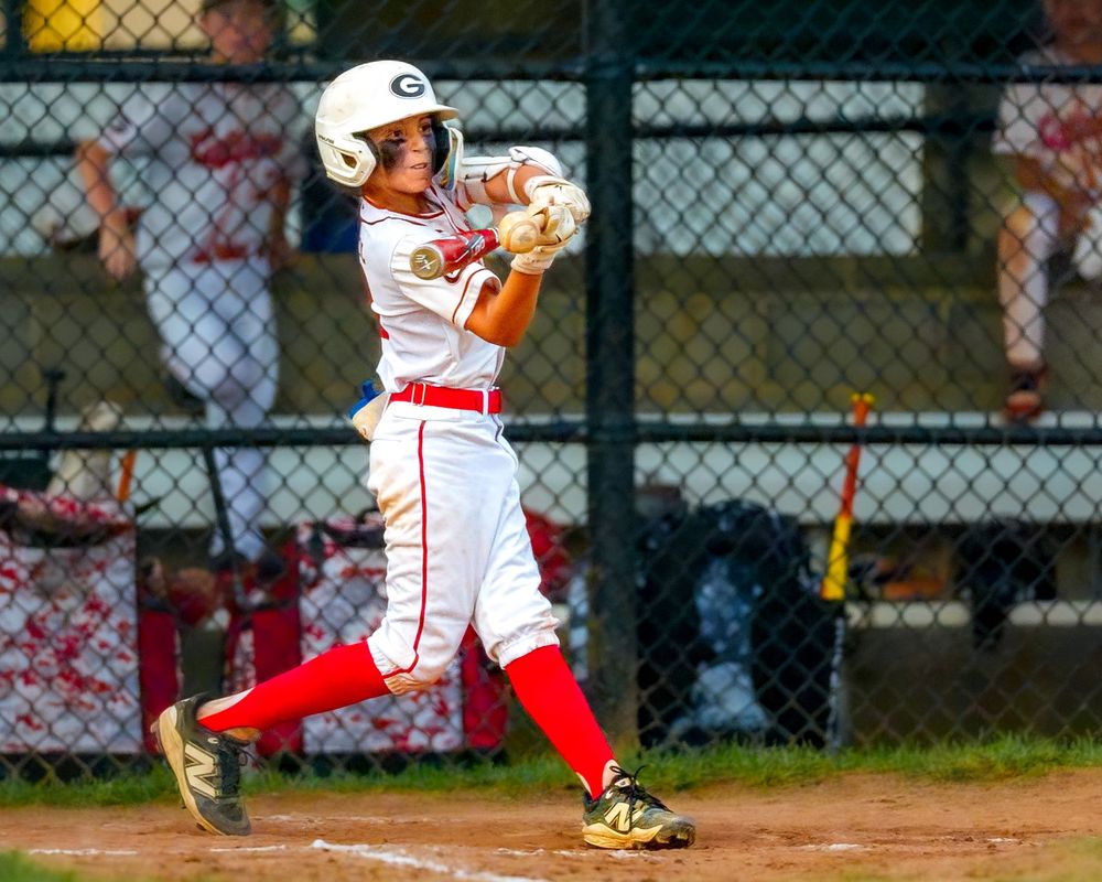 Youth baseball player batting during a game, focused at the plate, SportsFox Photography.