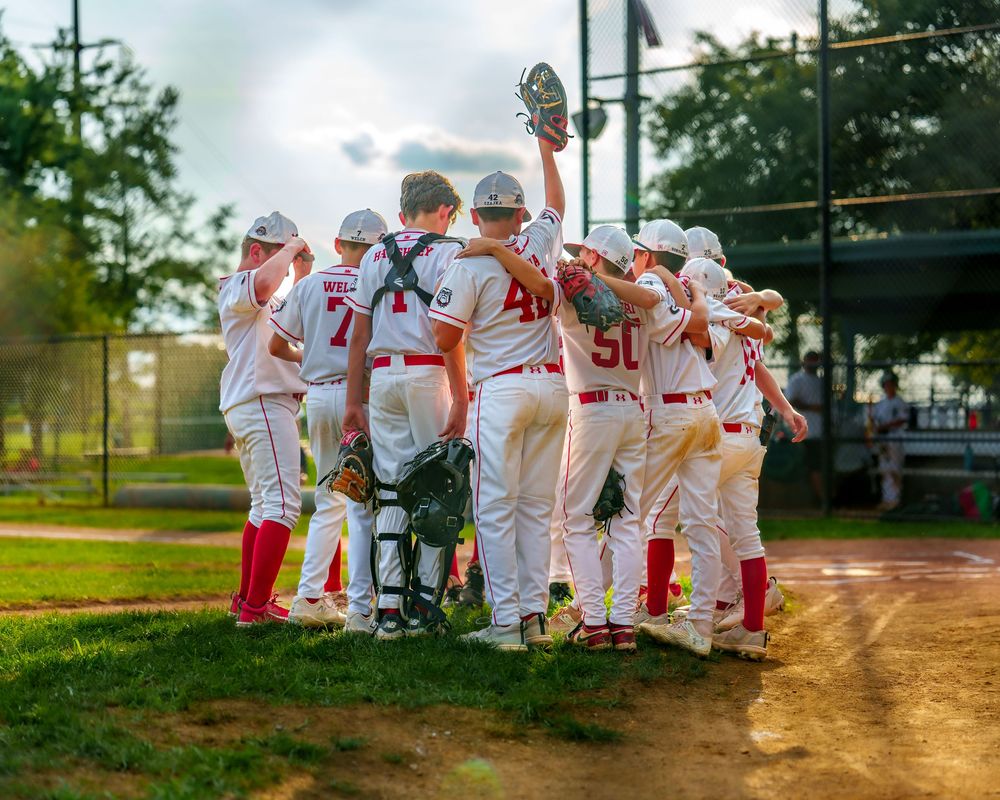 Cal Ripken youth baseball team huddled together on the field before the game, celebrating teamwork and excitement, SportsFox Photography.