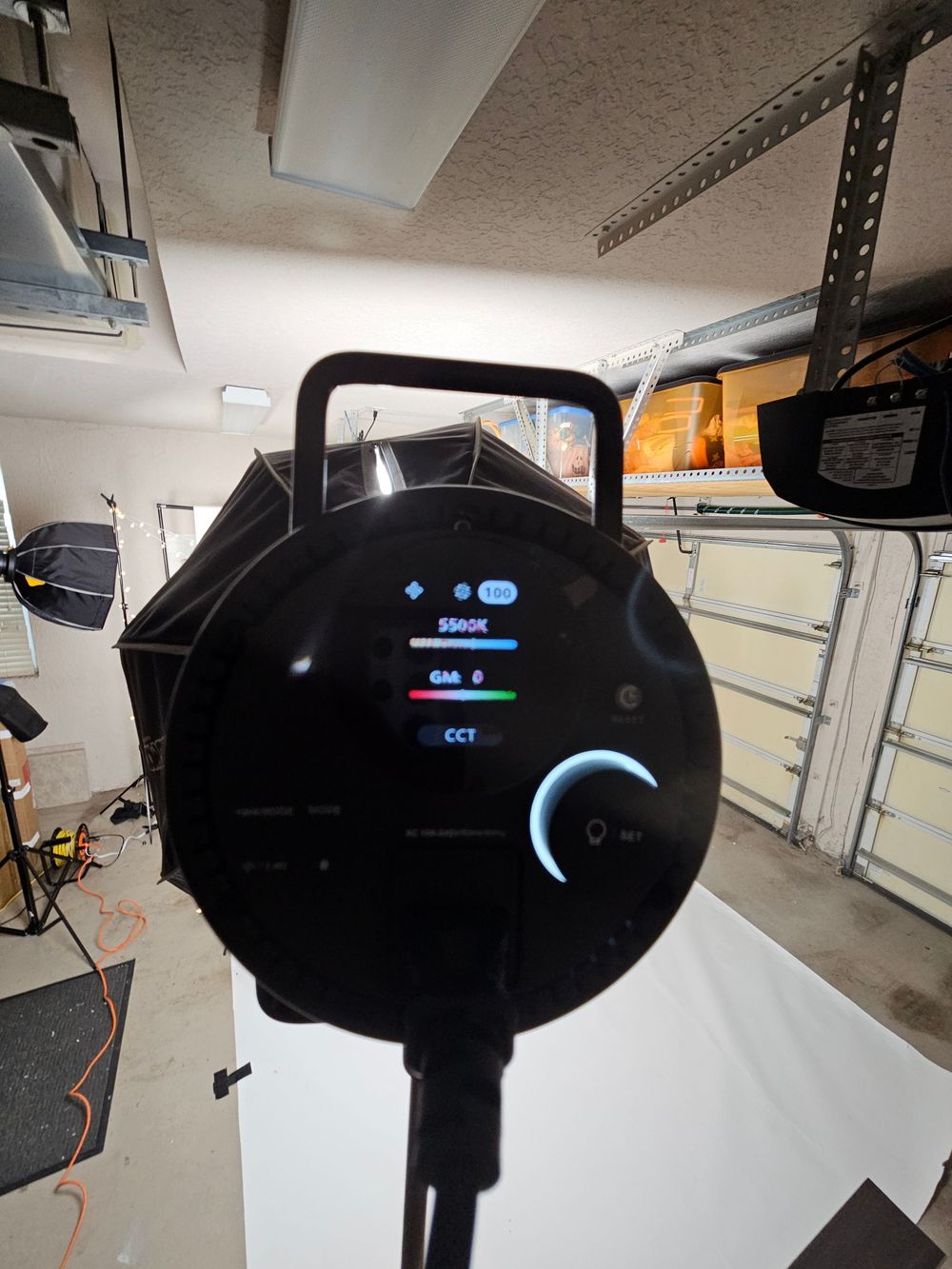 A black electric vehicle charging station mounted on a garage wall with blue LED indicators glowing.