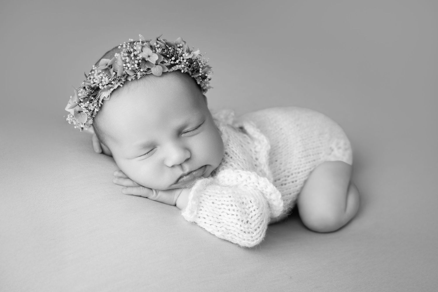 Monochrome series of sleeping newborn photos with delicate poses and soft lighting.