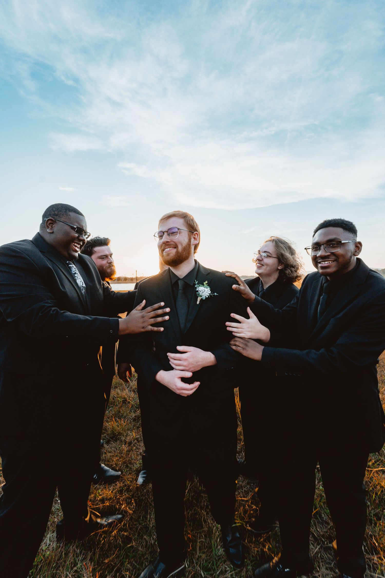 A sequence of photos showing groomsmen in black suits laughing and embracing outdoors during sunset.