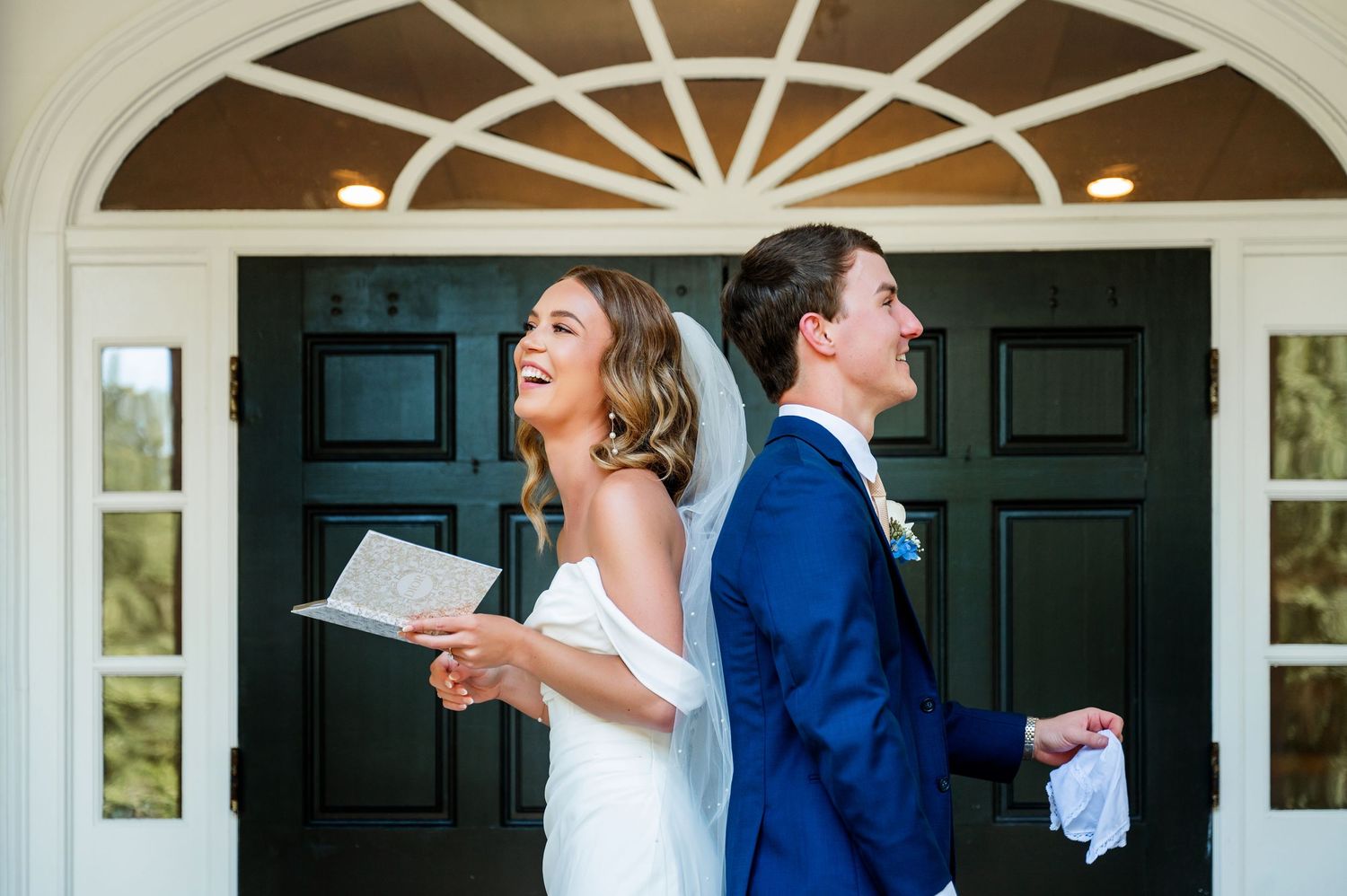 A couple shares a happy moment while reading letters on their wedding day in front of a black door.