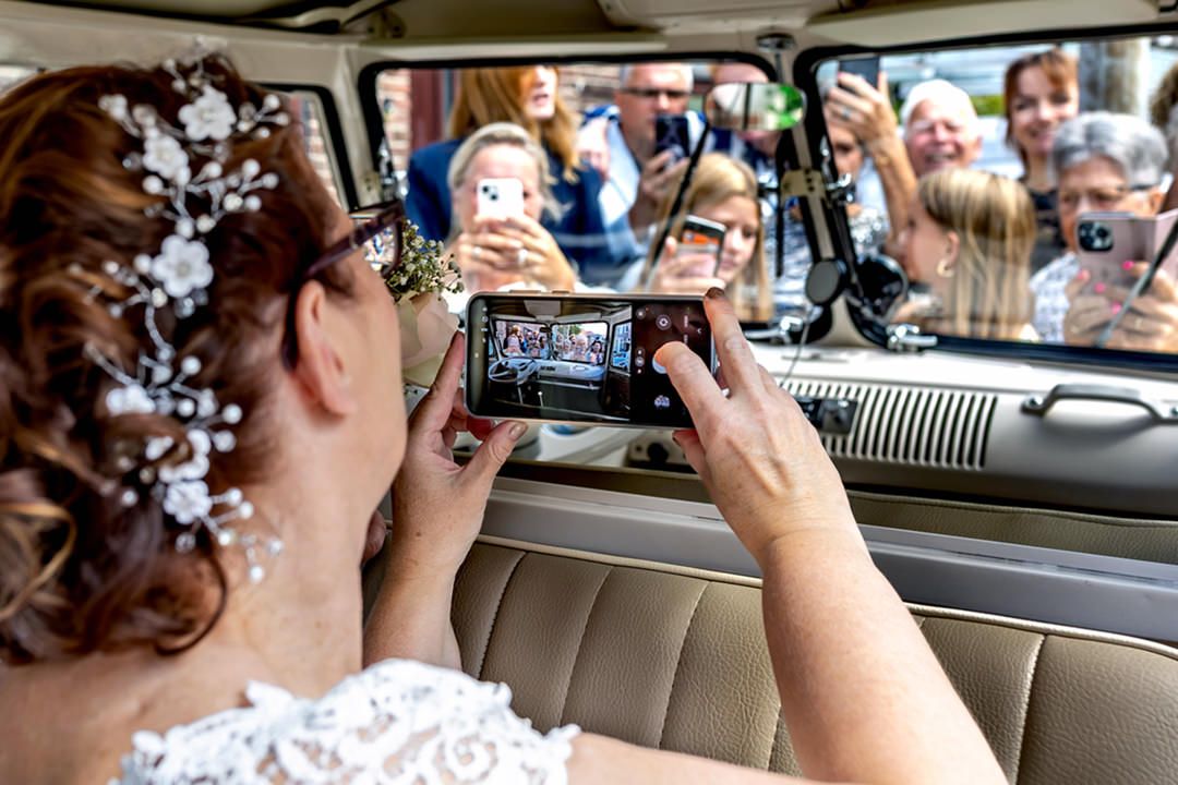 irsten maakt met haar telefoon een foto van alle aanwezige gasten terwijl ze in de Volkswagen vintage bus zit
