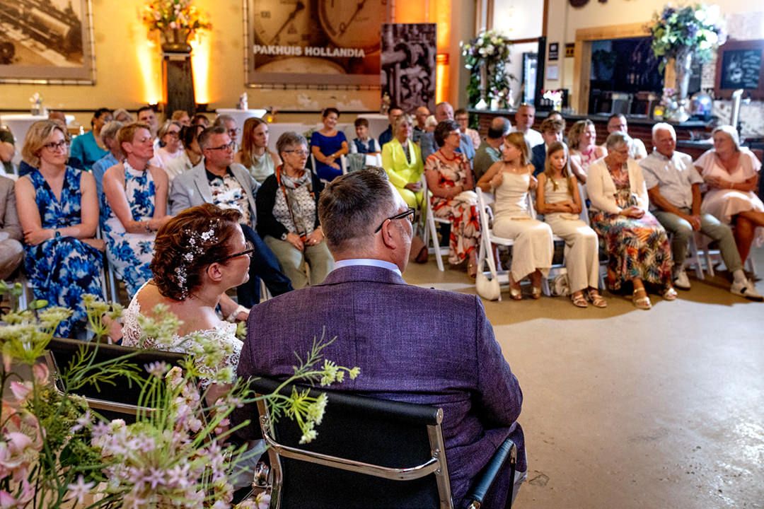 Ceremoniemoment met bruidspaar en aanwezige gasten in de trouwzaal bij De Stoomhal, Wormer
